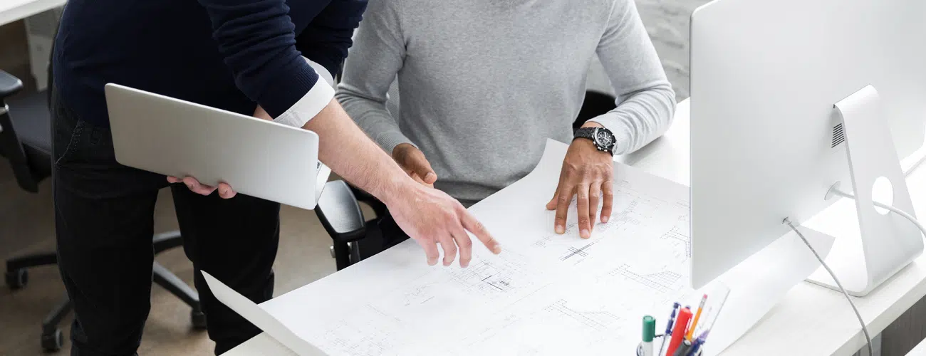 Architects collaborating on technical construction drawings for residential building development