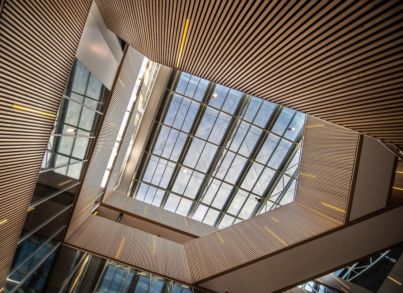 Looking up into a modern atrium with angled wood-slat cladding and a skylight