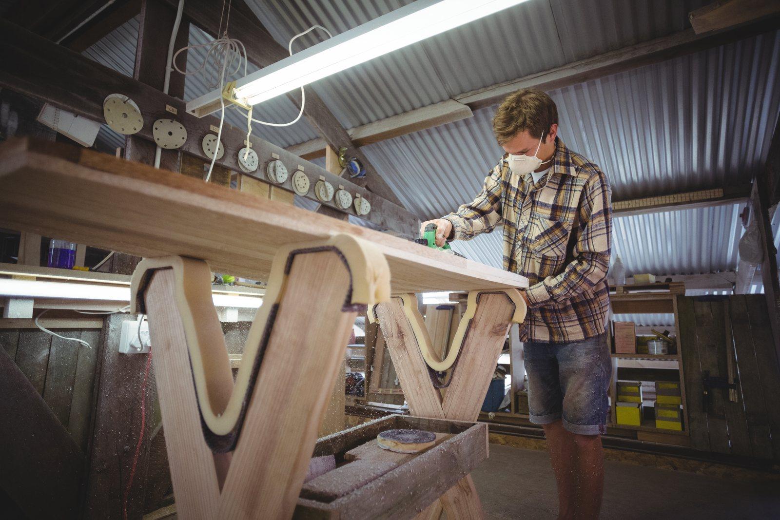 Worker shaping a curved board blank by hand in a small workshop
