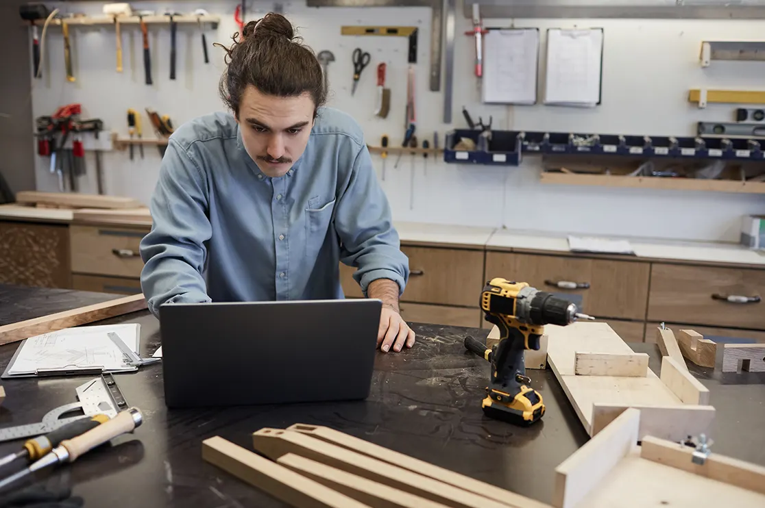 Carpenter reviewing traditional millwork shop drawings on a laptop